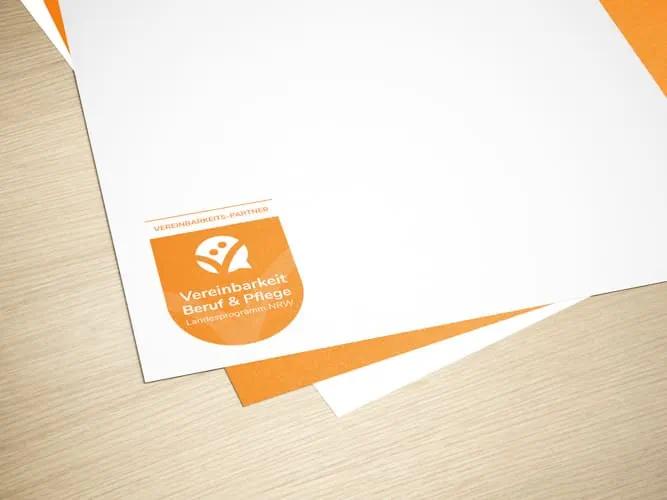 Briefpapier mit dem Logo und orangener Rückseite der Vereinbarkeit von Beruf und Pflege NRW
